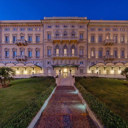 Gh Palazzo Suite & Spa Λιβόρνο Εξωτερικό φωτογραφία The photo shows a large, elegant building, likely a hotel or historic structure, illuminated at dusk. It features a classic architectural style with multiple balconies and ornate detailing on the façade. The building is framed by well-maintained gree