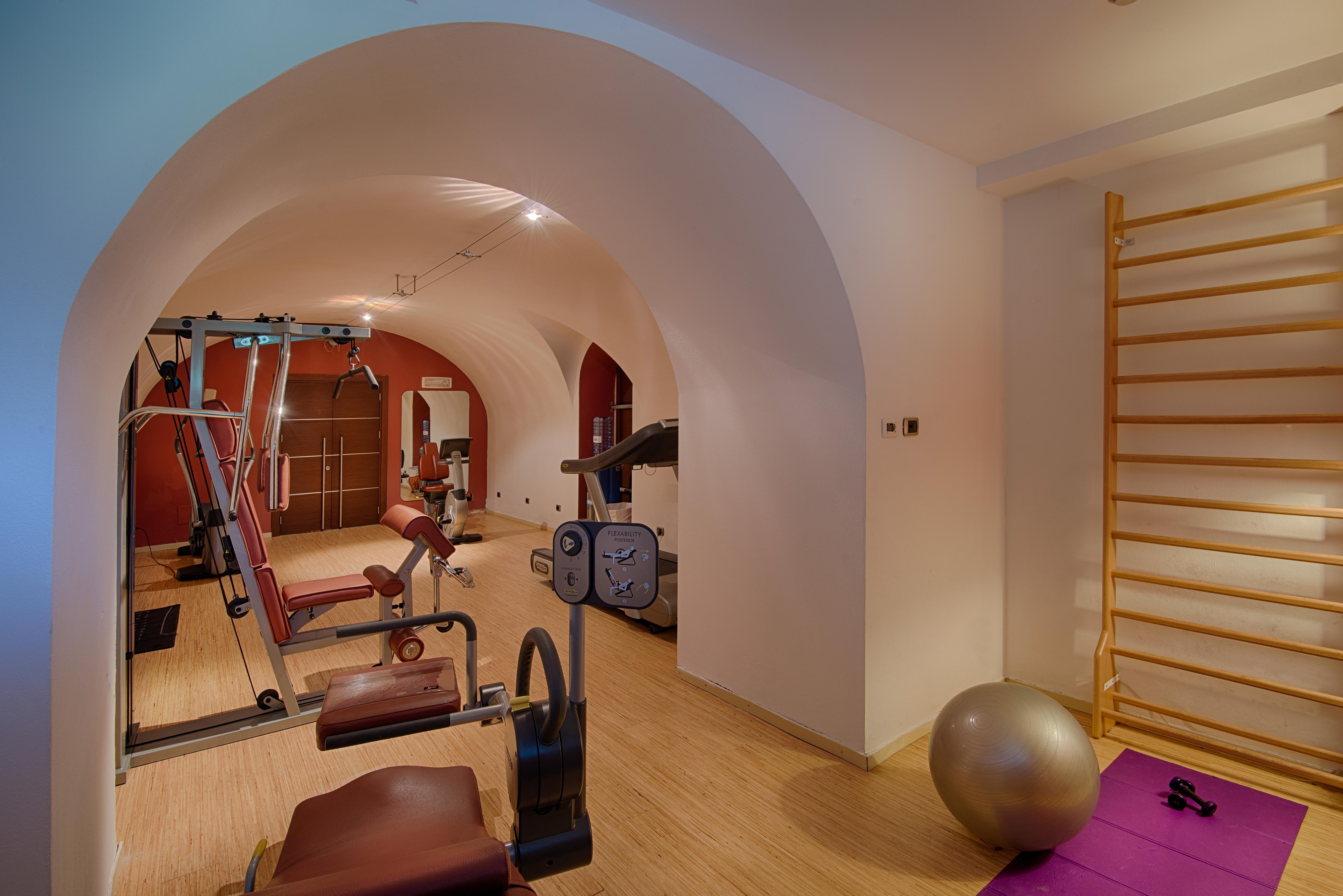 Gh Palazzo Suite & Spa Λιβόρνο Εξωτερικό φωτογραφία The photo shows a home gym or fitness area with a clean, modern design. It features exercise equipment such as a weight machine, a stationary bike, and a variety of workout mats. There is also a large exercise ball and a wooden wall bar for stretchin